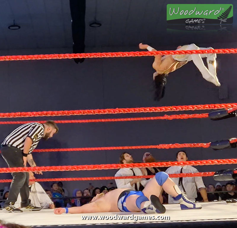 Wrestler Tee Hawke flying from the top rope and onto wrestlers outside the ring during a wrestling match - Aotearoa Wrestling - Woodward Games